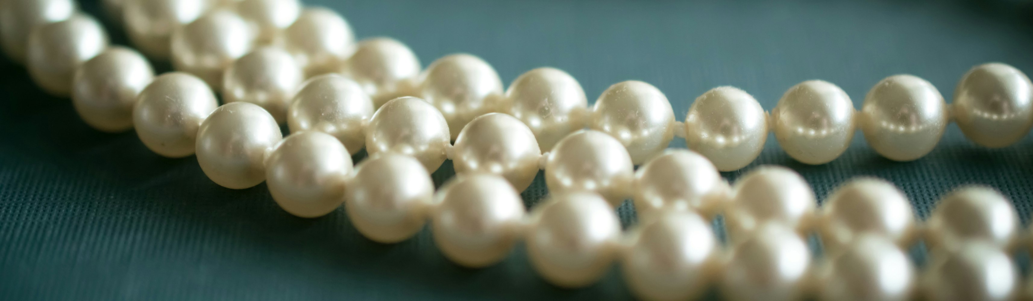 white pearl necklace on gray textile