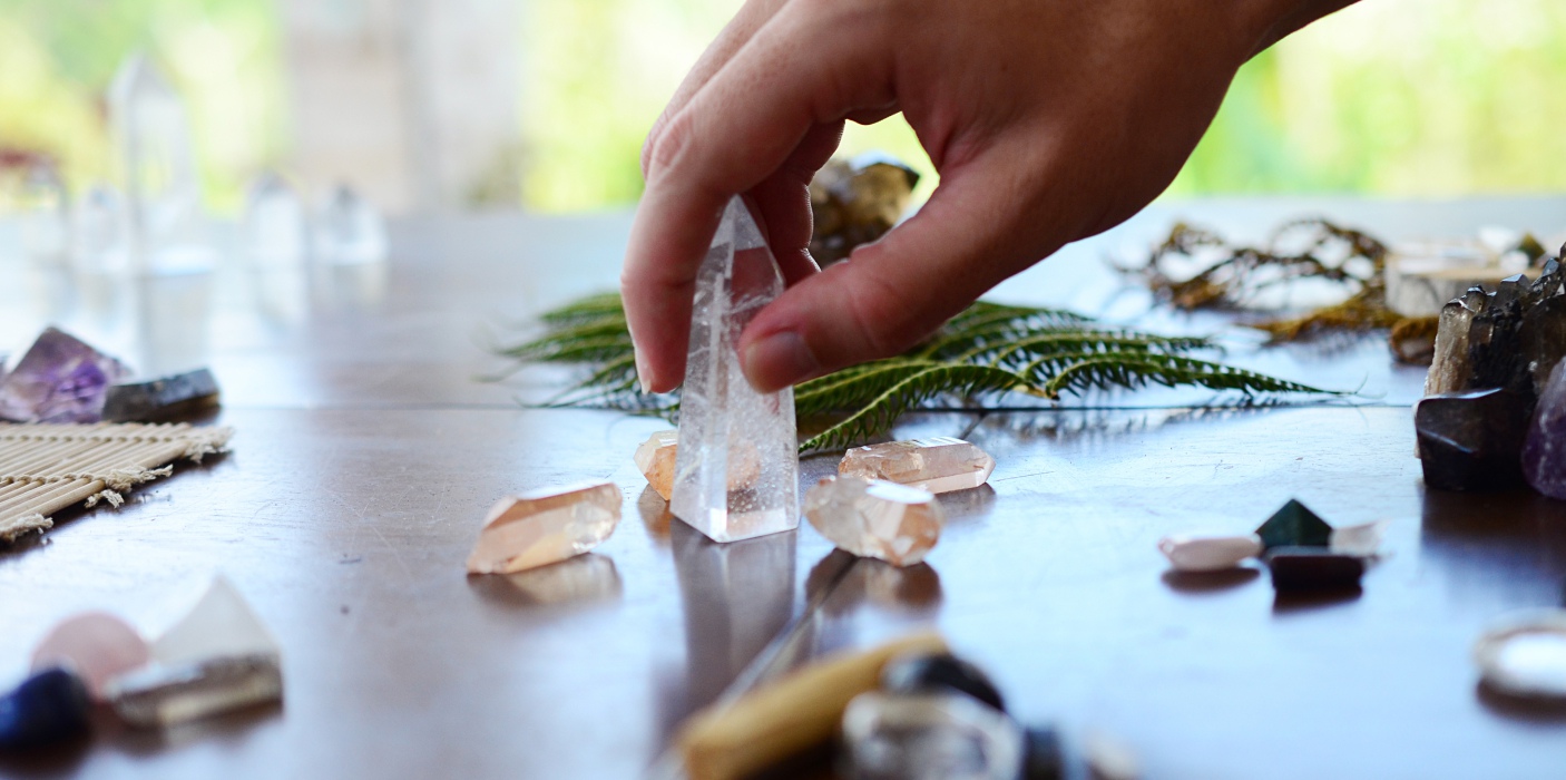 Beautiful Clear Quartz, variety of crystal on wood table. Bright Quartz crystal, healing crystal being held in hand. Woman holding quartz tower, crisp colors in natural lighting. Vibrant meditation