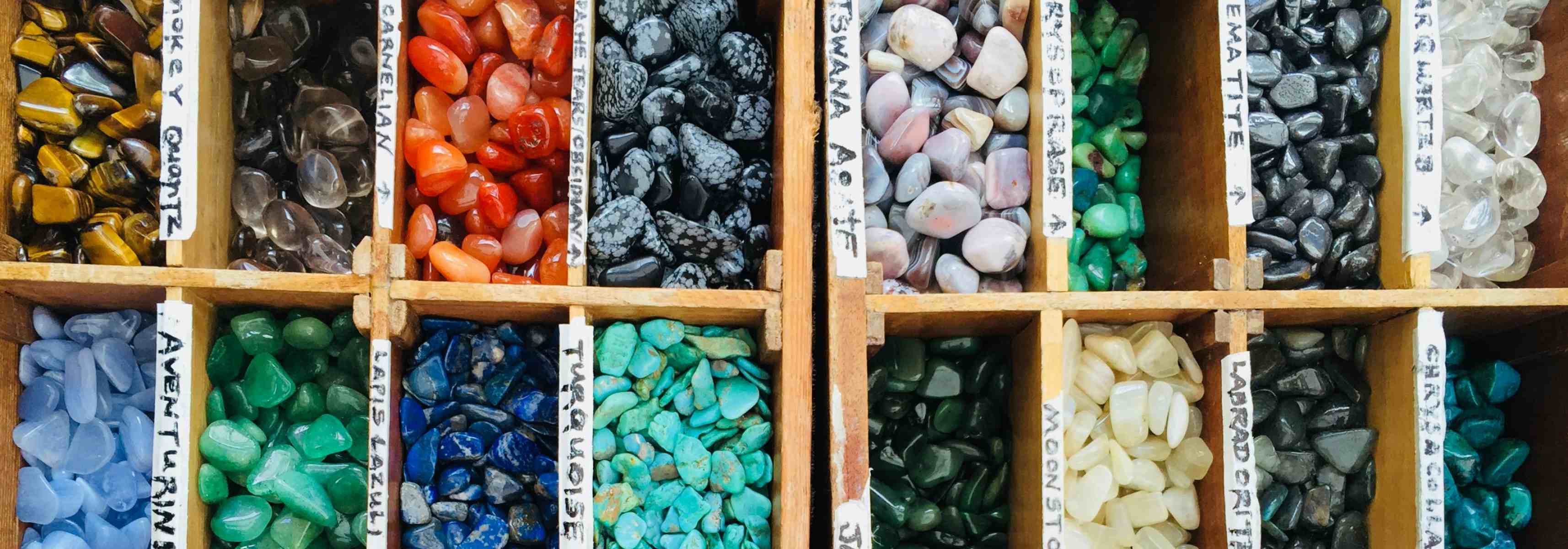 An assortment of different coloured gemstone in boxes