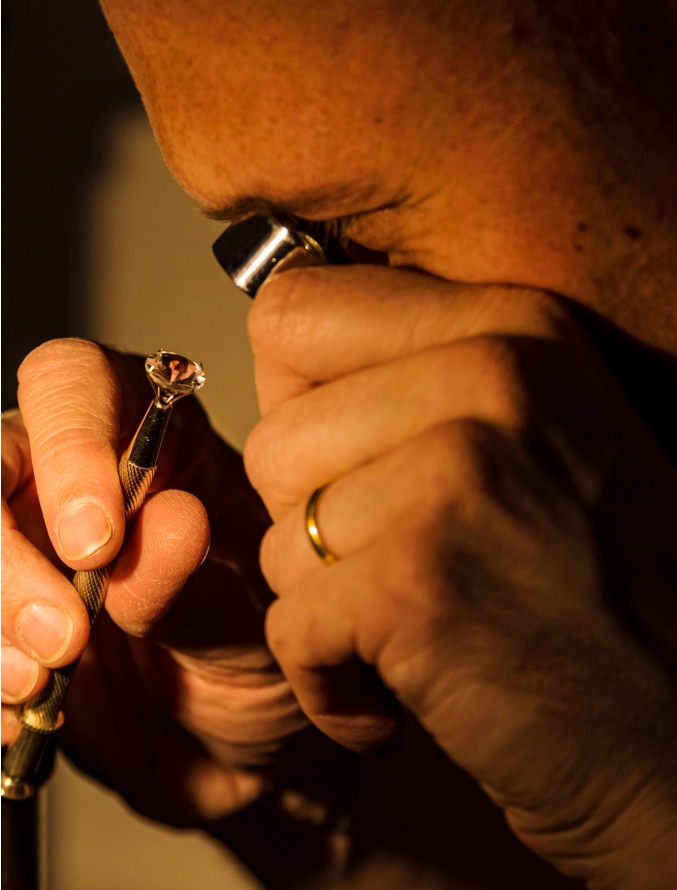 Craftsman appraising faceted gemstone with eyepiece